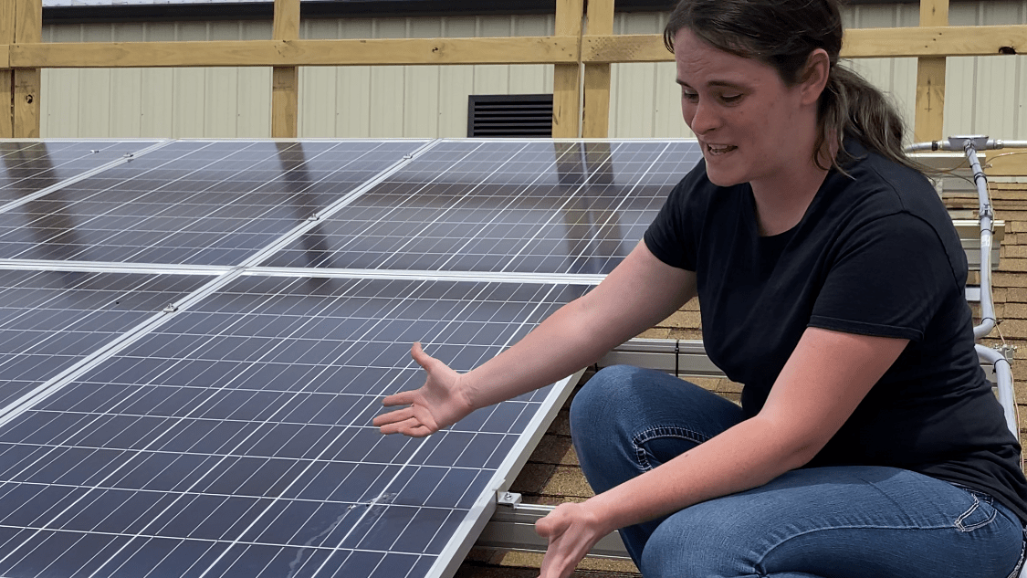 Christine gesturing to solar panels on residential roof